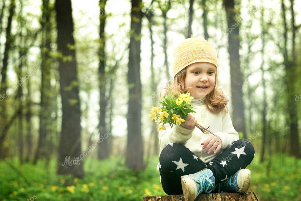 girl closeup smelling a yellow flower on a green background happy