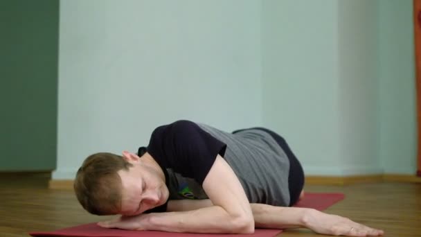 Sağlıklı bir stüdyoda uzanan bir adam yoga yapar — Stok video