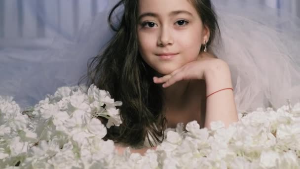 Όμορφο κορίτσι βρίσκεται στα λουλούδια και χαμόγελα, σε εσωτερικούς χώρους 4k — Αρχείο Βίντεο
