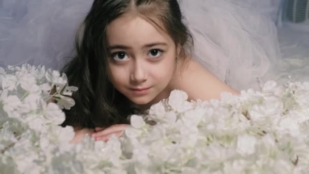 Vacker flicka ligger på blommor och leenden, inomhus 4k — Stockvideo