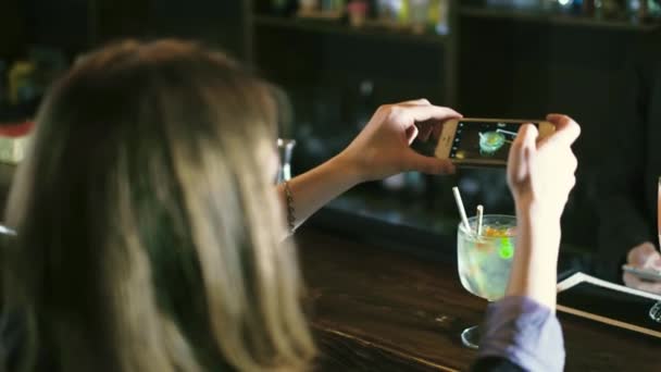 Красивая женщина фотографирует коктейль в баре 4k — стоковое видео