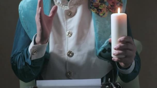 Ο θαυματοποιός γράφει σε μια γραφομηχανή, κρατώντας ένα κερί 4k — Αρχείο Βίντεο