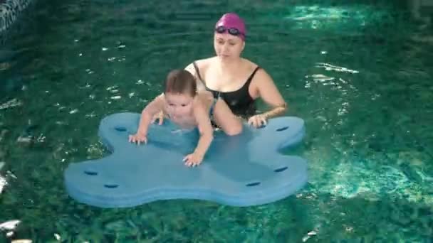 Feliz madre enseñando a su hijo en la piscina 4k — Vídeos de Stock