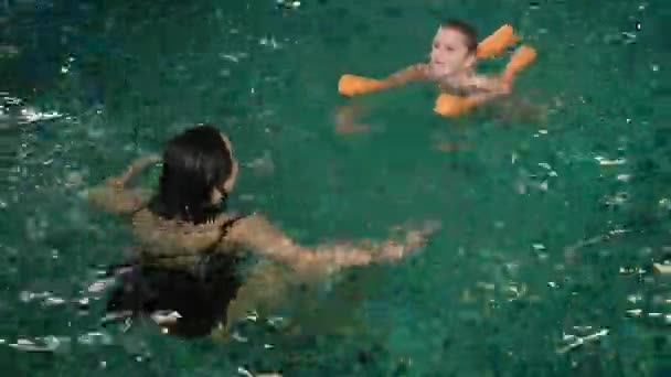 Feliz madre enseñando a su hijo en la piscina 4k — Vídeo de stock