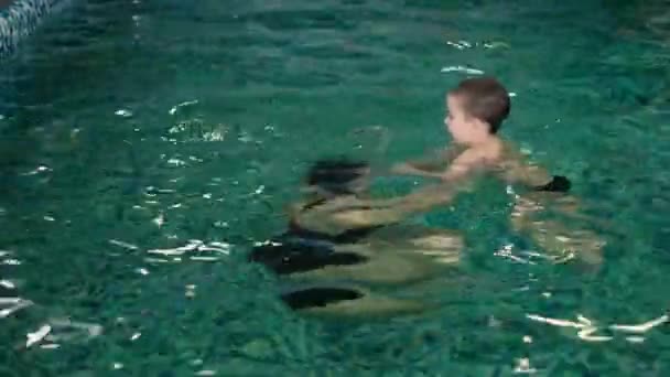 Feliz madre enseñando a su hijo en la piscina 4k — Vídeos de Stock