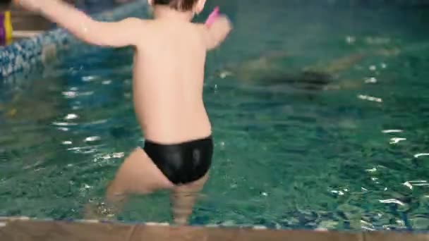 Feliz madre enseñando a su hijo en la piscina 4k — Vídeo de stock