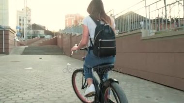 Güzel kadın uzun boylu 4 k bina yakınındaki bir bisiklet ile gidiyor