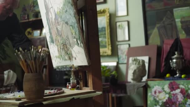 Un artista de edad avanzada escribe una foto en su estudio 4k — Vídeo de stock