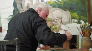 Yaşlı bir sanatçı bir resim onun stüdyosunda 4 k yazıyor.