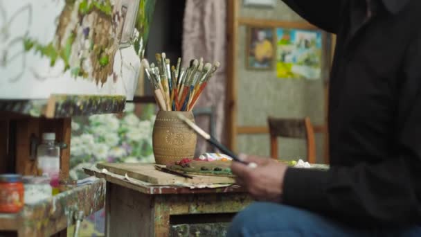 An elderly artist writes a picture in his studio 4k — Stock Video