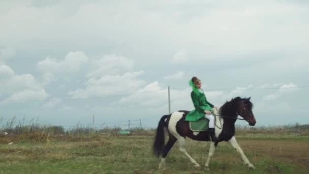 Женщина в зеленом костюме едет верхом на лошади 4К — стоковое видео