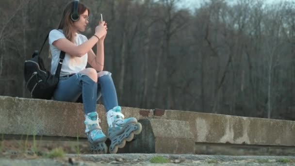 Mooie vrouw luisteren naar muziek in rolschaatsen aan de kust 4k — Stockvideo