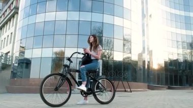 Güzel kadın uzun boylu 4 k bina yakınındaki bir bisiklet ile gidiyor
