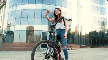 Güzel kadın uzun boylu 4 k bina yakınındaki bir bisiklet ile gidiyor