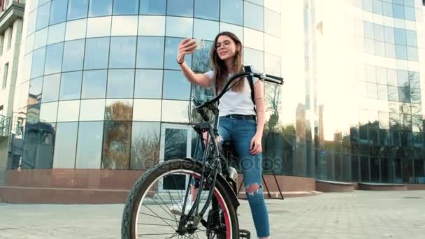 Bella donna guida una bicicletta vicino a un edificio alto 4k — Video Stock