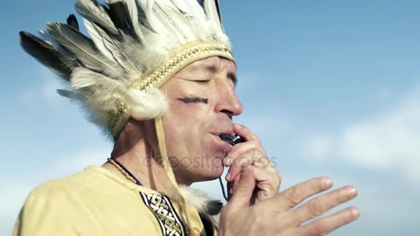 Um índio em um traje nacional toca flauta na margem do rio 4k — Vídeo de Stock