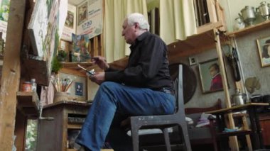 Yaşlı bir sanatçı bir resim onun stüdyosunda 4 k yazıyor.