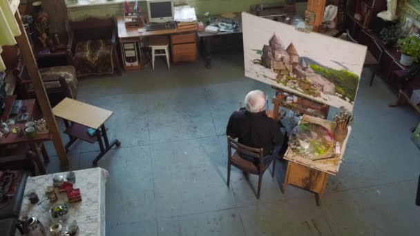 Un artista de edad avanzada escribe una foto en su estudio 4k — Vídeo de stock