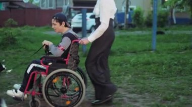 Anne oğlu ile bir köpek tekerlekli sandalye ile yürüyor
