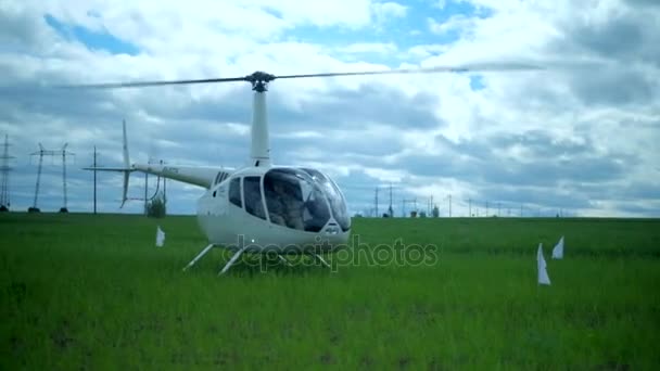 Вертолет приземляется на зеленое поле, лопасти вращаются hd — стоковое видео