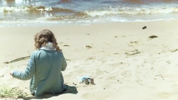 Mulher que fica em uma praia com flor no dia ensolarado 4k — Vídeo de Stock