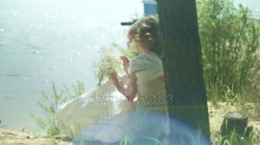 Çiçek ile bir plajda güneşli gün 4 k kalan kadın içinde beyaz elbise