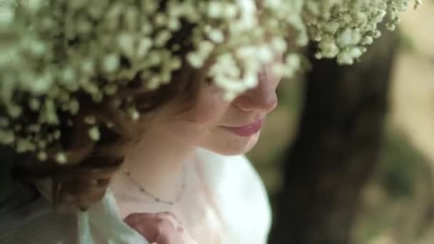 Hermosa mujer en un vestido blanco en el bosque con flores 4k — Vídeos de Stock