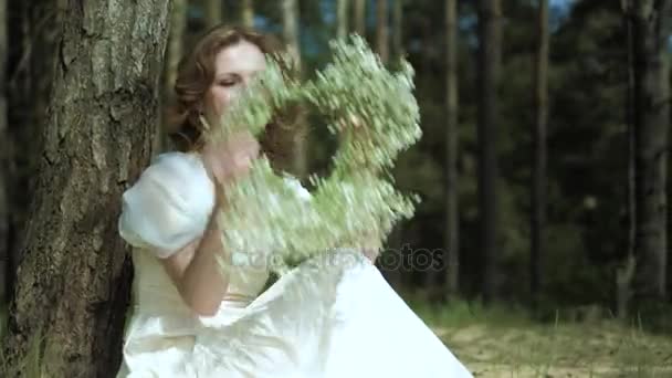 Vacker kvinna i en vit klänning klänning i skogen med blommor 4k — Stockvideo