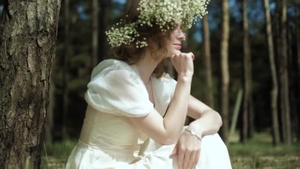 Hermosa mujer en un vestido blanco en el bosque con flores 4k — Vídeo de stock