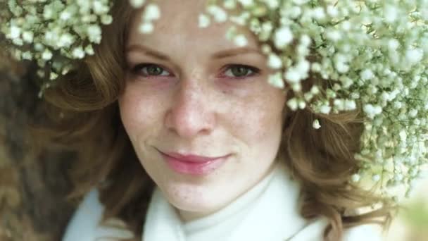 Hermosa mujer en un vestido blanco en el bosque con flores 4k — Vídeos de Stock