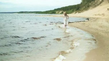 Çiçek ile bir plajda güneşli gün 4 k kalan kadın içinde beyaz elbise