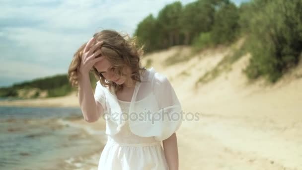 Женщина в белом платье на пляже с цветами в солнечный день 4k — стоковое видео