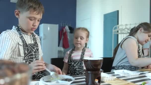 Close-up portret jonge baker onderzoekt en aanraken met behulp van vinger chocolade 4k — Stockvideo