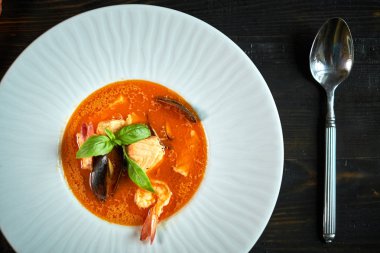 Domates sosu ve Hindistan cevizi sütü eski bir ahşap tepsi ile ev yapımı deniz mahsulleri çorbası