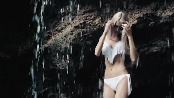 Красива жінка в бікіні, що стоїть біля водоспаду — стокове відео