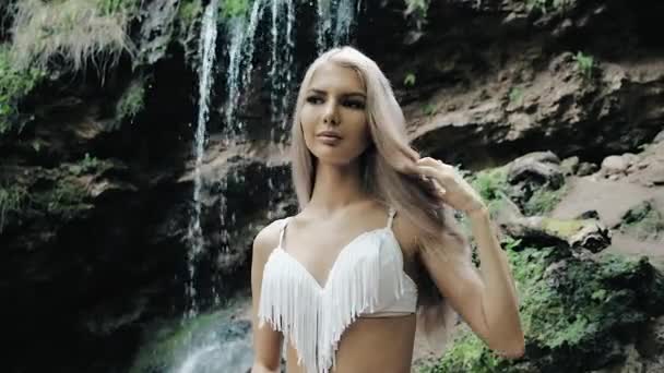 krásná žena v bikinách stojící poblíž vodopádu