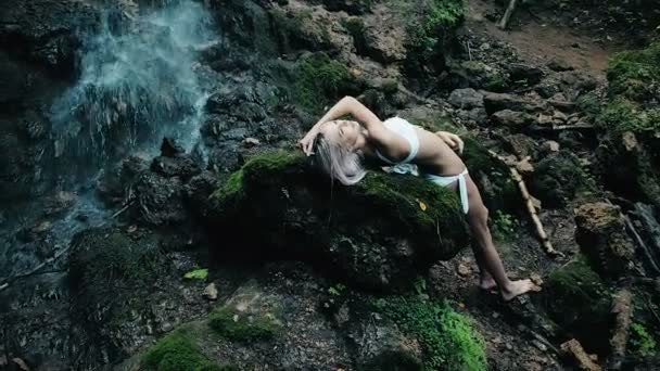 Красивая женщина в бикини, стоящая у водопада — стоковое видео