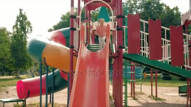 Enfant glissant sur une glissière dans le parc, Petite fille jouant sur une aire de jeux, Enfants — Video