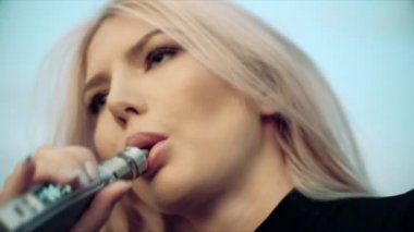 Moda makyaj ile açık, genç güzel kadın bir elektronik sigara 4k gelen buhar ile