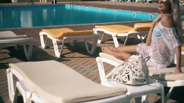 Havuz başında video klip güzel kadın şezlong genç kadına yalan rahatlatır