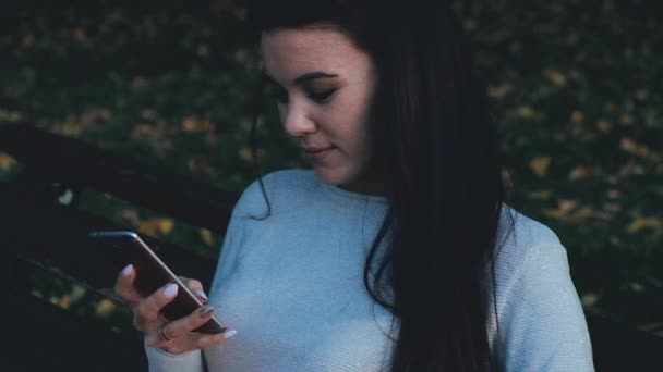 Una hermosa joven profesional está teniendo una conversación telefónica, al aire libre en la ciudad por la noche. Ella sonríe. — Vídeos de Stock