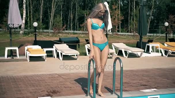 UNA MUJER HERMOSA RELAJA UNA PISCINA CON AGUA AZUL — Vídeo de stock