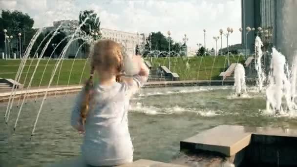 Hermosa chica lanza barcos de papel en una fuente — Vídeos de Stock