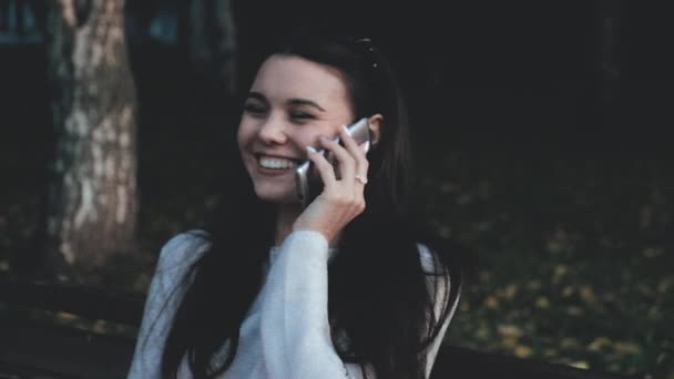 Una hermosa joven profesional está teniendo una conversación telefónica, al aire libre en la ciudad por la noche. Ella sonríe. — Vídeos de Stock