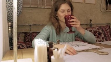 Gülümseyen ve kameraya bakarak çay içme ve kafede, rahatlatıcı mutlu kız.