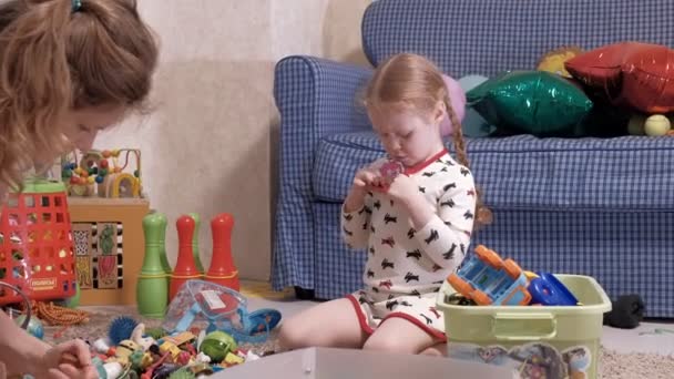 Jovem mãe com filhinha sentada no chão e brincando com brinquedos . — Vídeo de Stock