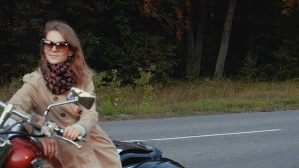 Jovem com cabelo castanho senta-se em uma moto perto de uma estrada . — Vídeo de Stock