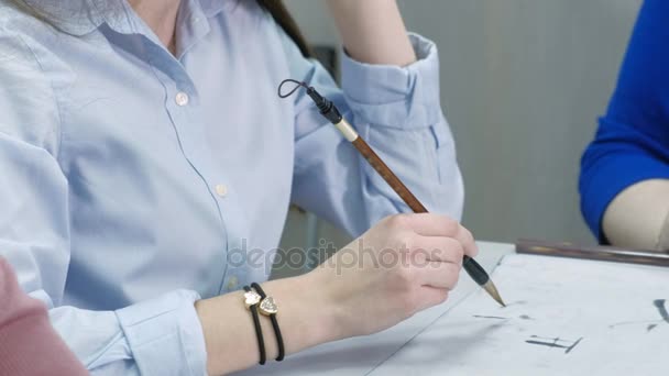 Mulher ensinando adolescente como escrever personagens chineses na aula de caligrafia. Estudante aprendendo a escrever com pincel, tinta, papel e professor ajudando-a. Escola, educação — Vídeo de Stock