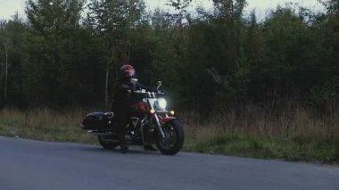 Bir adam bir motosiklet orman içinde bir yola rides