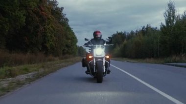 Bir adam bir motosiklet orman içinde bir yola rides